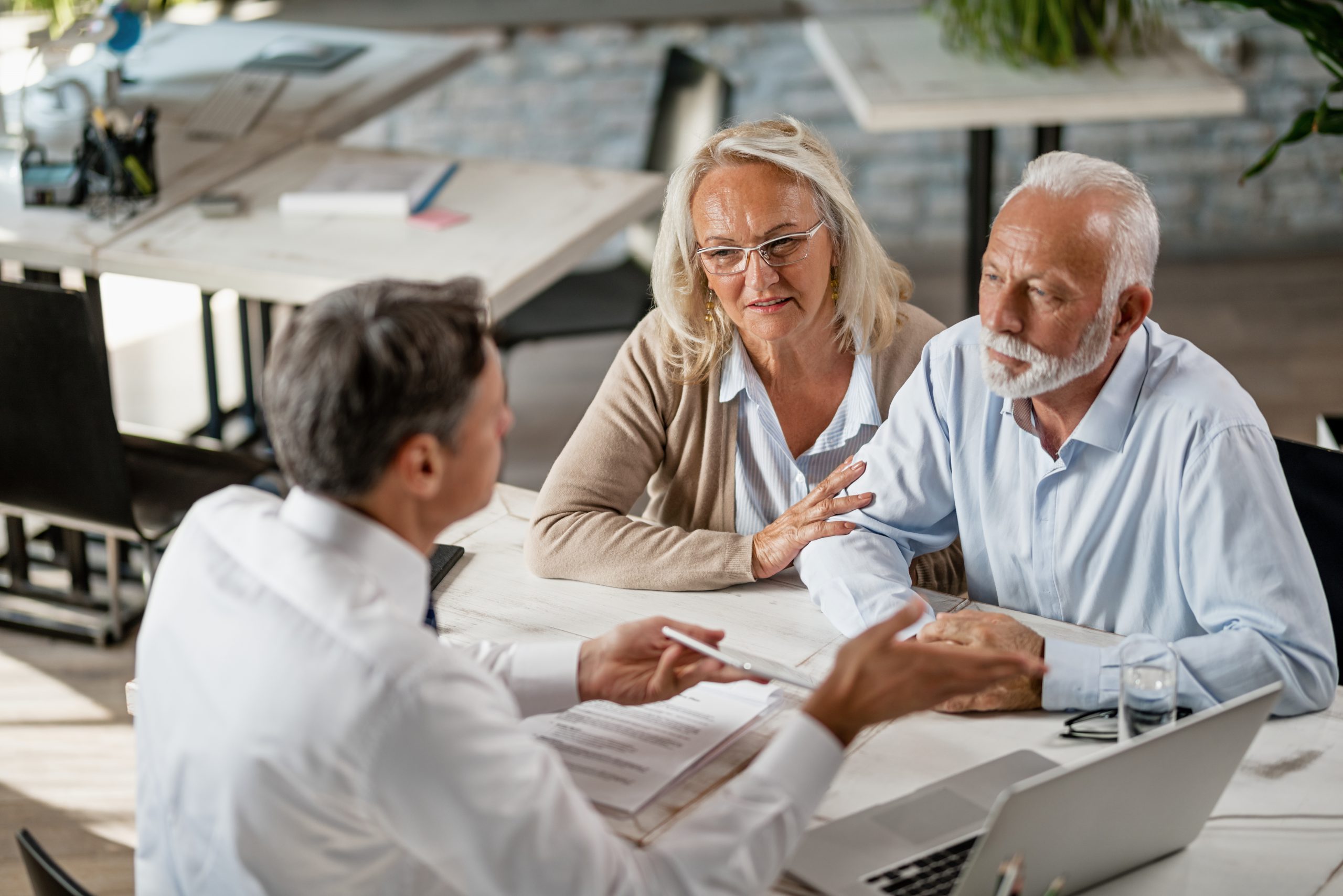 Senior couple talking to real estate agent on a meeting in the office.
